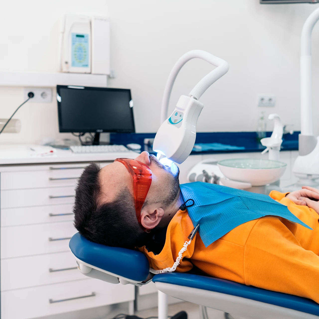 man getting professional teeth whitening service at dentist office
